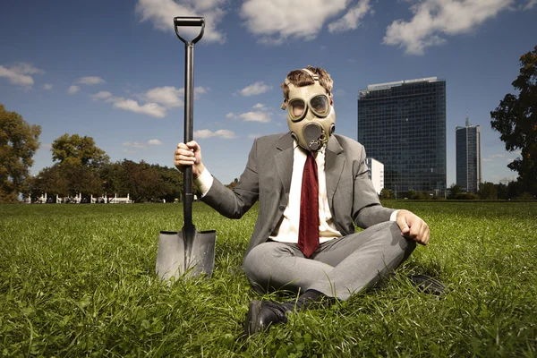 Dirty sitting manager in gas mask with spade — Stock Photo, Image