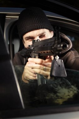 Saldırı tüfekli bir adam arabada bekliyor.