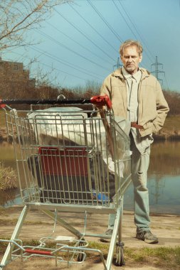 Arazisi alışveriş arabasında olan yaşlı dilenci.