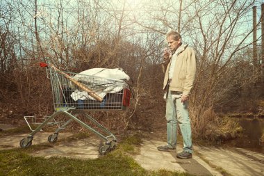 Arazisi alışveriş arabasında olan yaşlı dilenci.