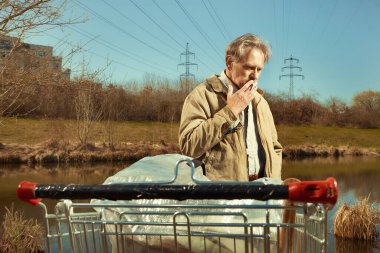 Arazisi alışveriş arabasında olan yaşlı dilenci.