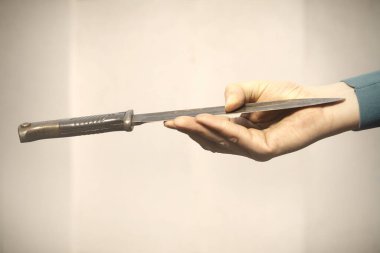 Uzun bir bıçak tutuyor, bıçağını fırlatmaya hazır.