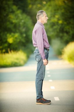 Older man in violet shirt posing in park for portrait
