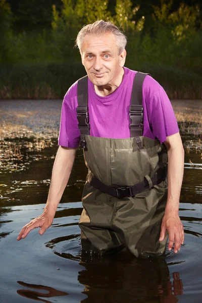 Water quality analyst dressed in chest wader collecting samples