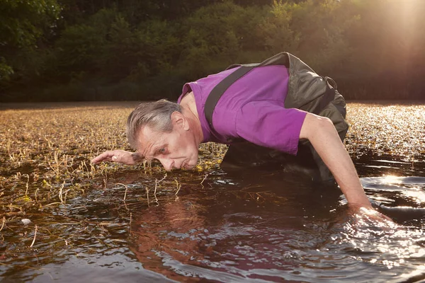 Water quality analyst dressed in chest wader collecting samples