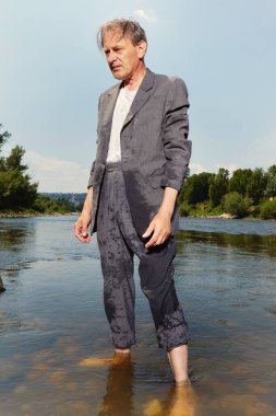 Manager in grey suit became crazy of hot weather and cooling in river