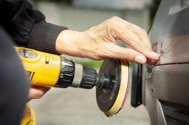 Toplamda bir adam caddede arabasının hasarı üzerine matkapla çalışıyor.