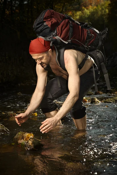 Hombre en bufanda roja refrescante en arroyo — Foto de Stock