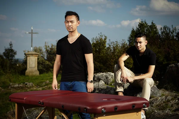 Two Asian masseurs outdoor with massage table — Stock Photo, Image