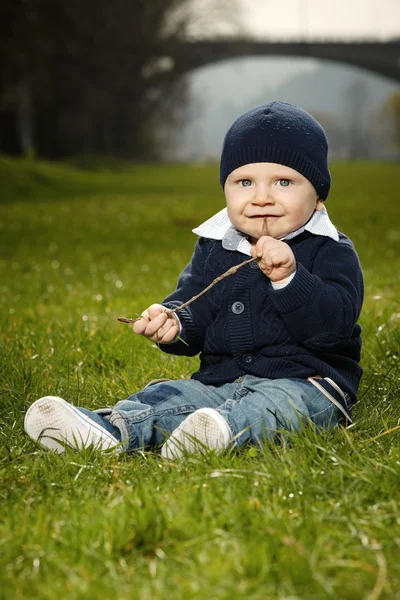 Kleine jongen sittin in park op gras — Stockfoto