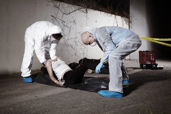 Crime scene team handling woman body to bag — Stock Photo, Image