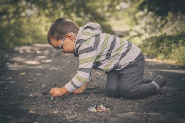 Yetişkin bir adam ve oğlu doğada klasik misketleri eğitiyorlar.