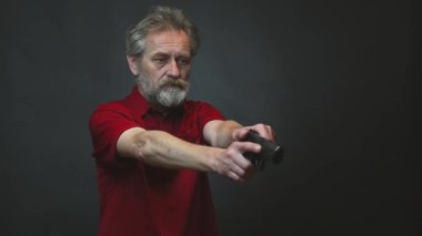 Yaşı ilerlemiş yaşlı bir adam arka planda izole edilmiş tabancayla operasyon yapıyor.