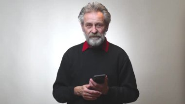 Yaşı ilerlemiş yaşlı bir adam arka planda izole akıllı telefon ile çalışıyor.