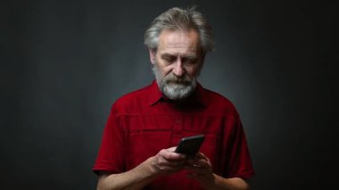 Yaşı ilerlemiş yaşlı bir adam arka planda izole akıllı telefon ile çalışıyor.