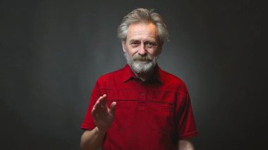 Yaşı ilerlemiş yaşlı bir adam arka planda tek başına el sallıyor.