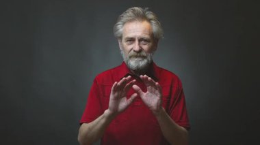 Yaşı ilerlemiş yaşlı bir adam arka planda tek başına el sallıyor.