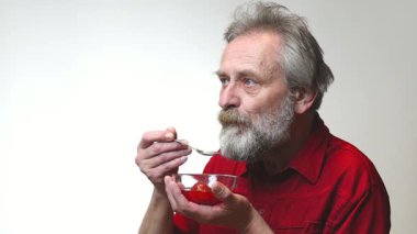 Yaşı ilerlemiş yaşlı bir adam arka planda tek başına yiyip içiyor.