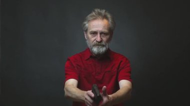 Yaşı ilerlemiş yaşlı bir adam arka planda izole edilmiş tabancayla operasyon yapıyor.