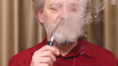 Yaşlı adam detaylı video görüntülerinde kapalı mekanda elektronik sigara içiyor.