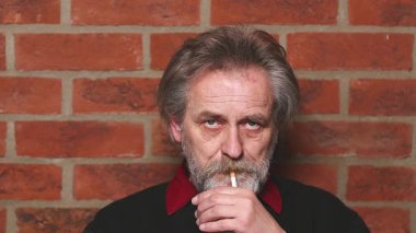 Yaşlı adam balkonda sigara içiyor. Detaylı video çekimlerinde klasik sigara.