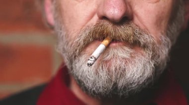 Yaşlı adam balkonda sigara içiyor. Detaylı video çekimlerinde klasik sigara.