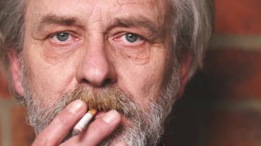 Yaşlı adam balkonda sigara içiyor. Detaylı video çekimlerinde klasik sigara.