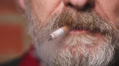 Yaşlı adam balkonda sigara içiyor. Detaylı video çekimlerinde klasik sigara.