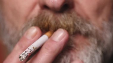 Yaşlı adam balkonda sigara içiyor. Detaylı video çekimlerinde klasik sigara.