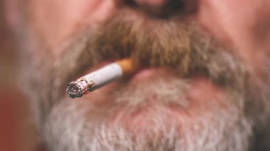 Yaşlı adam balkonda sigara içiyor. Detaylı video çekimlerinde klasik sigara.