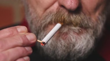 Yaşlı adam balkonda sigara içiyor. Detaylı video çekimlerinde klasik sigara.