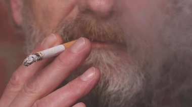 Yaşlı adam balkonda sigara içiyor. Detaylı video çekimlerinde klasik sigara.