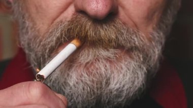 Yaşlı adam balkonda sigara içiyor. Detaylı video çekimlerinde klasik sigara.