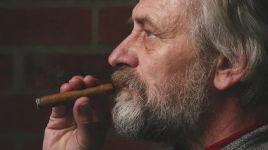 Yaşlı adam balkonda sigara içiyor. Detaylı video görüntülerinde büyük bir puro.