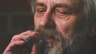 Yaşlı adam balkonda sigara içiyor. Detaylı video görüntülerinde büyük bir puro.