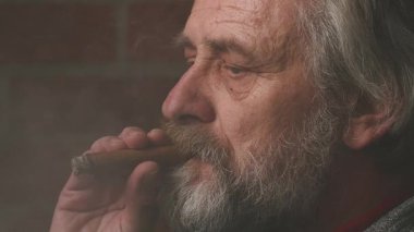 Yaşlı adam balkonda sigara içiyor. Detaylı video görüntülerinde büyük bir puro.