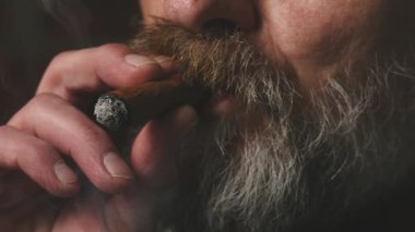 Yaşlı adam balkonda sigara içiyor. Detaylı video görüntülerinde büyük bir puro.