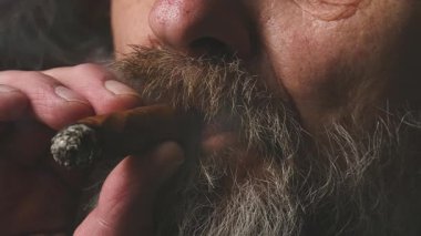 Yaşlı adam balkonda sigara içiyor. Detaylı video görüntülerinde büyük bir puro.