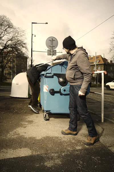 Man disturbing homeless exploring containers — Stock Photo, Image