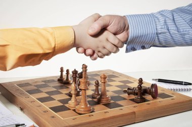 Yetişkin bir satranç oyuncusu genç bir satranç oyuncusunu zaferinden dolayı tebrik eder..