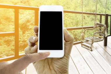 El ele tutuşun ve ekrandaki akıllı telefona dokunun paslı demir koltukta patlak bir ışıkla sallanın.