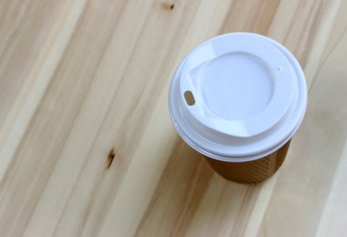 Tahta bir masada beyaz kağıt bir fincan kahve.