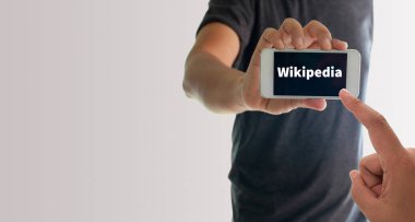 Görüntüde Wikipedia metniyle akıllı telefonu tutan bir adam