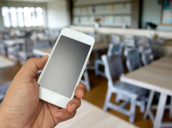 hand holding the smartphone on blur restaurant background,Transactions by smartphone concept