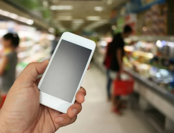 hand holding the smartphone on supermarket in blurry for background