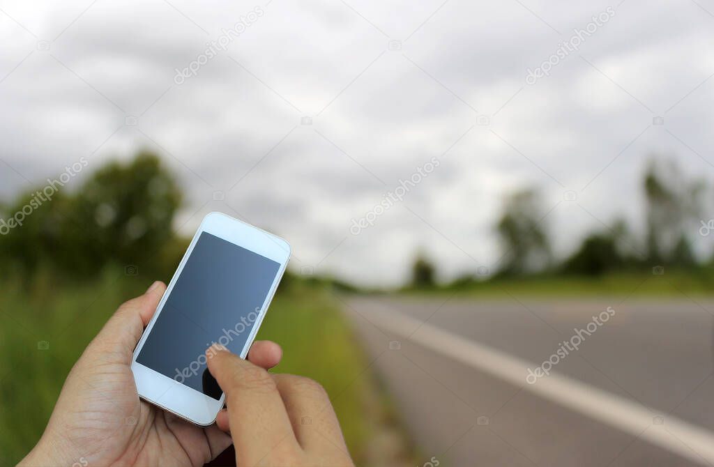 hand holding the smartphone on blur of road running through the way