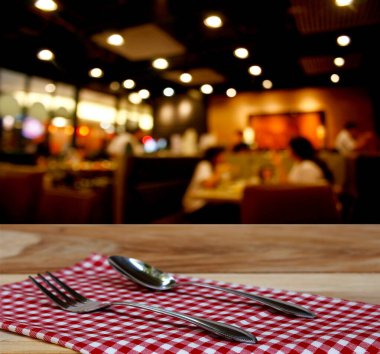 Lokantanın arka planındaki kareli masa örtüsü ve müşterinin çatal ve kaşığı Bokeh ile bulanık.