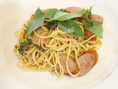 Beyaz tabakta füme sosisli spagetti.