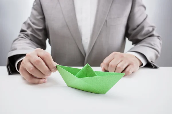 Empresario con un barco de papel verde —  Fotos de Stock