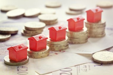  houses resting on pound coin stacks  clipart